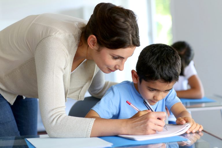 Teacher helping young boy with writing